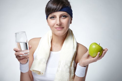 Kvinne holder et glass vann og et eple