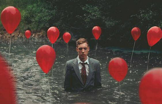 Mann står i dypt vann med ballonger