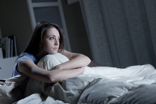 Deprimert kvinne sitter i sengen