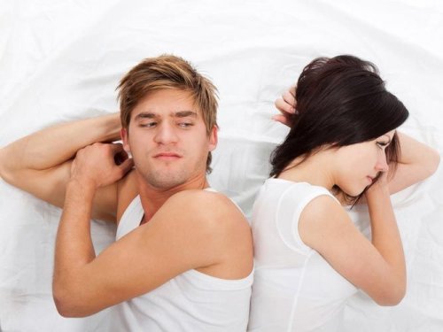 Mann og kvinne rygg mot rygg i sengen
