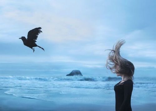 kvinne og fugl ved havet