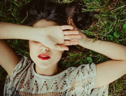 kvinne ligger i gresset med hånden foran øynene