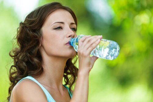 kvinne drikker fra en plastflaske