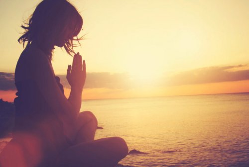 Kvinne mediterer i solnedgang