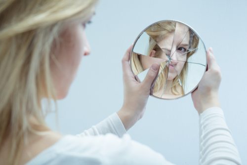 Kvinne ser i ødelagt speil