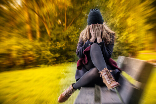 Kvinne med generalisert angstlidelse sitter på en benk i parken
