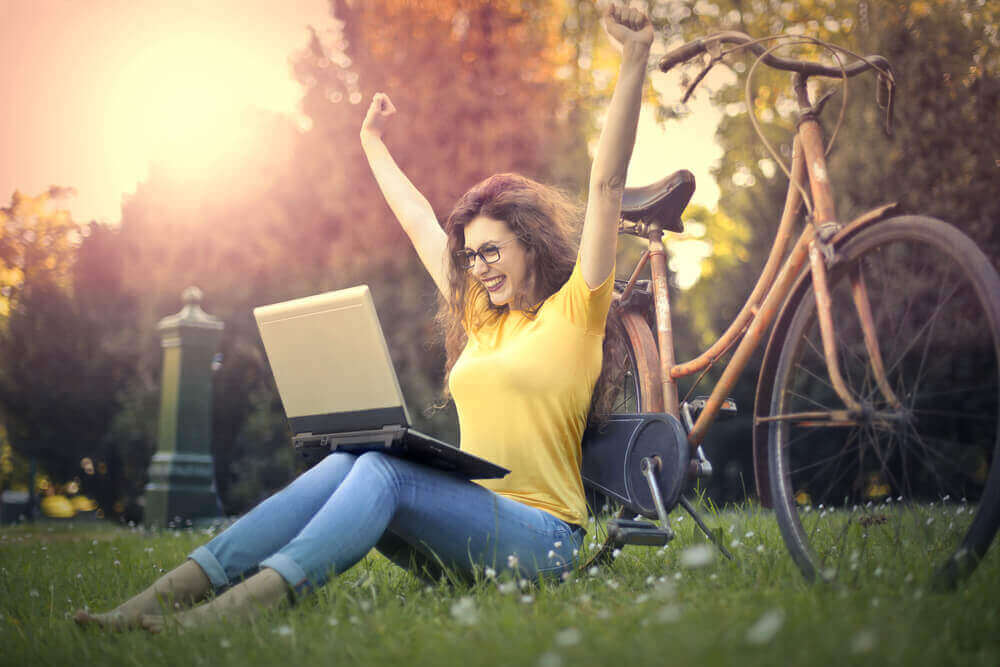 Kvinne med sykkel og PC i parken