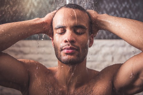 Mann som tar en varm dusj for å redusere nakkesmerter