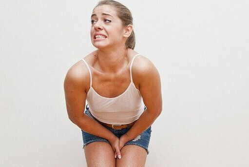 Kvinne med smerte under vannlating, noe som er symptomer på eggstokkreft