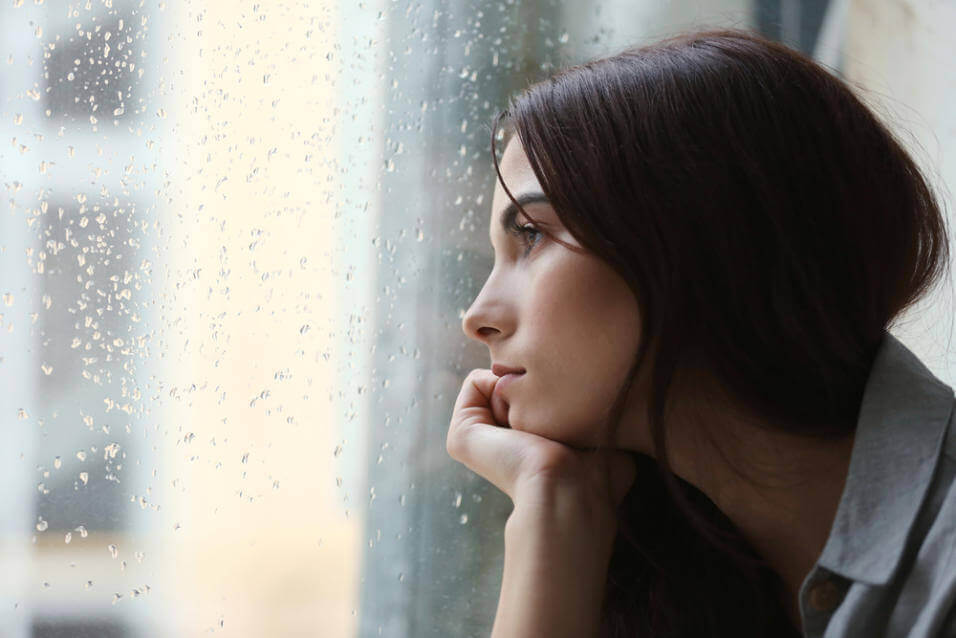 Kvinne med depresjon ser ut av vindu
