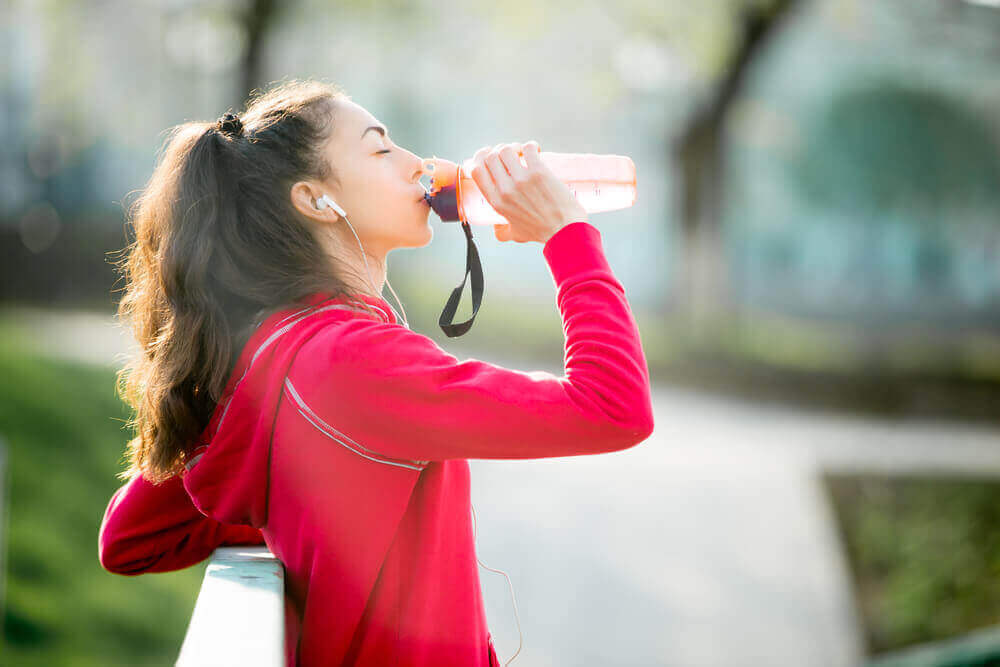 Kvinne drikker energidrikk etter trening