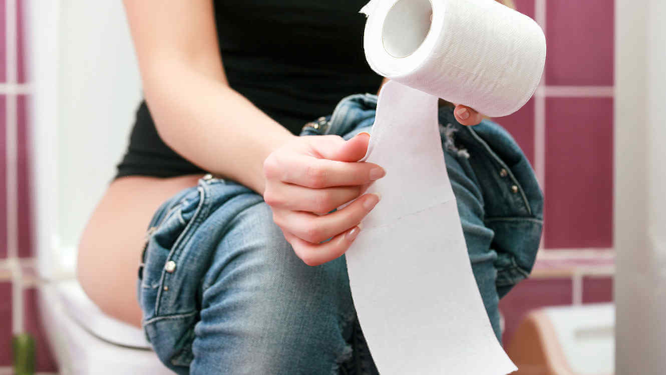 Kvinne sitter på toalettet