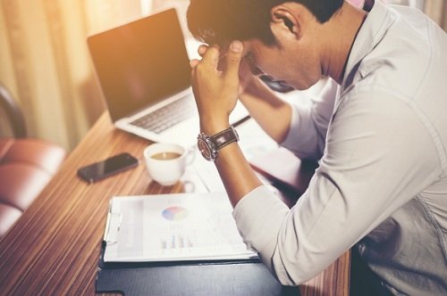 Ung mann med hodepine ved skrivebordet sitt på et kontor