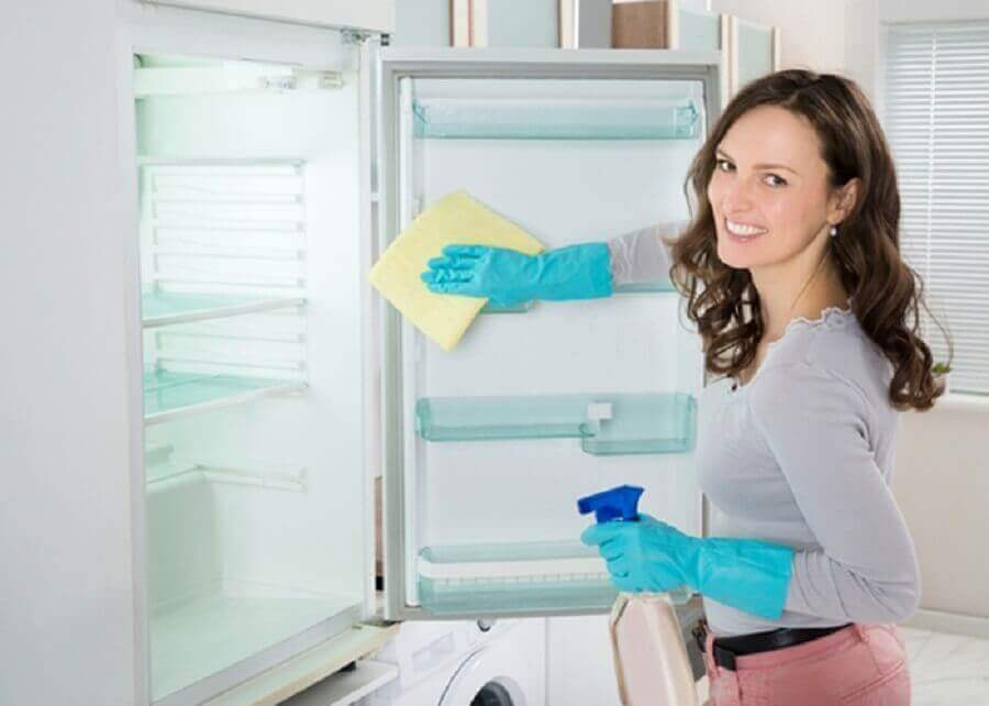 Kvinne rengjør kjøleskapet