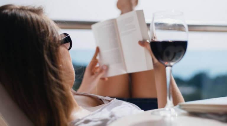 Kvinne leser og drikker rødvin