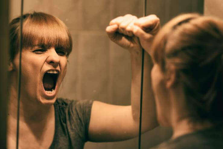 Kvinne kjefter på seg selv i speilet