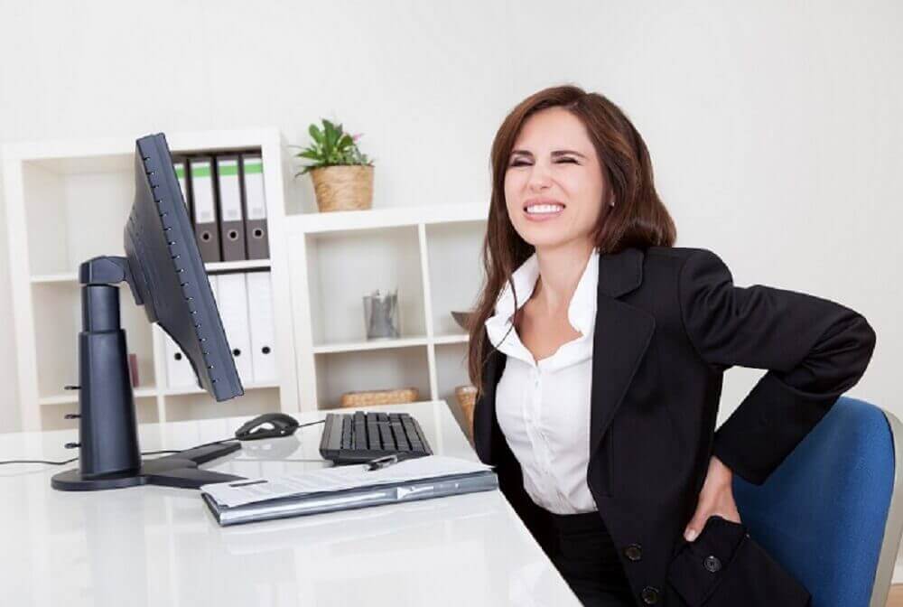 Kvinne på kontoret med ryggsmerter