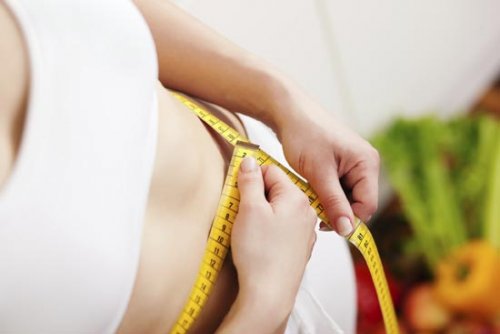Kvinne måler magen med målebånd
