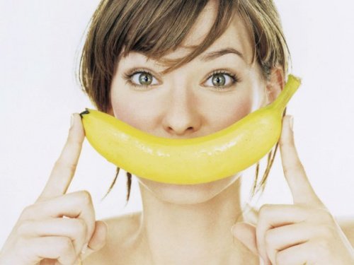 Kvinne holder en banan foran munnen som et smil