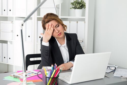 En kvinne som er trøtt på kontoret sitt.