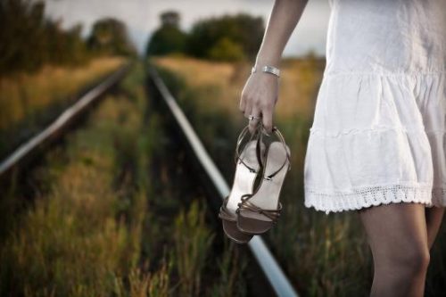 Kvinne går med sko i hendene