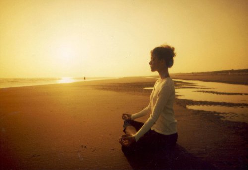 Kvinne mediterer på stranden