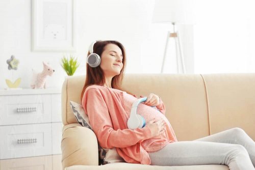 Gravid dame som hører på musikk med babyen sin