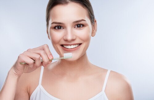 Kvinne pusser tennene med tannkrem med kokosolje