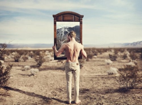 Mann som ser på ødelagt speil