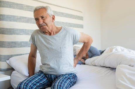 Mann med leddsmerter sitter på sengekanten