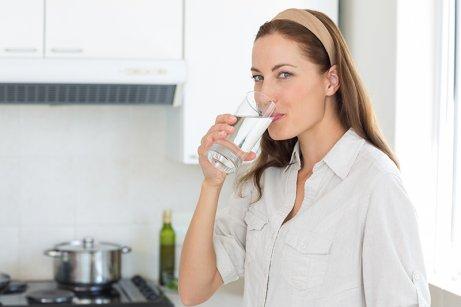 Kvinne drikker vann for å stramme opp huden