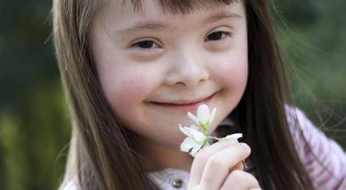 Barn med Downs syndrom lukter på en blomst