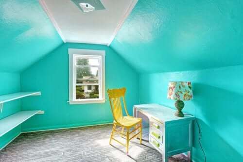 De beste fargene for et barns soverom: Et rom med livlige blå vegger med et skrivebord, en lampe og en gul stol.
