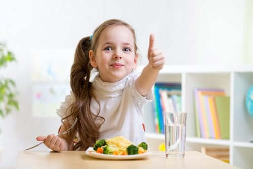 Ditt barns kosthold: En jente som spiser og gir tommelen opp.