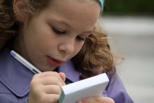En jente som øver på staving i en notisblokk.