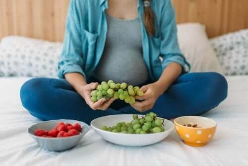Trygge medisiner: En kvinne som sitter på en seng med tre boller med frukt foran seg.