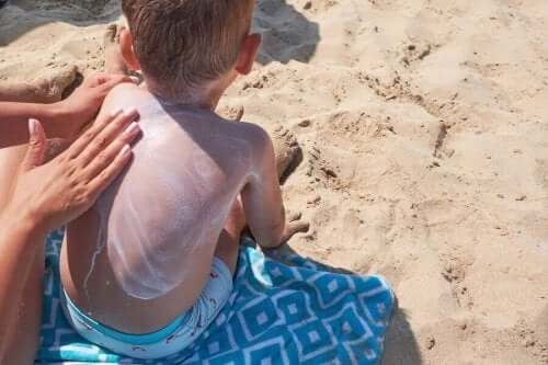 En mor som bruker solkrem på sønnens rygg.