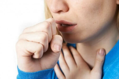En kvinne som hoster med neven foran munnen