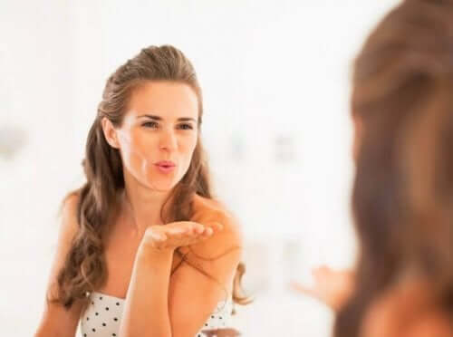 En kvinne som sender et slengkyss til speilbildet sitt