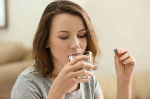 Kvinne drikker vann og tar en pille