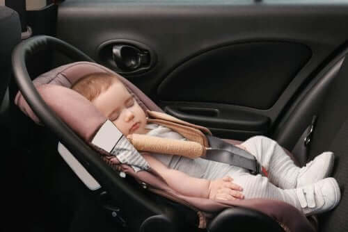 En baby som sover i en bil, ubekymret for deformasjonsplagiocefali.