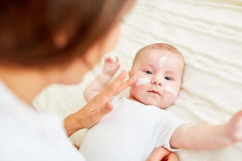  En kvinne som smører krem i ansiktet til en baby.