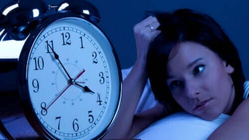 En kvinne som stirrer på klokken sin, ikke i stand til å sove.