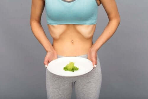 En kvinne med diabetes og bulimi som holder en tallerken med et liten porsjon salat.