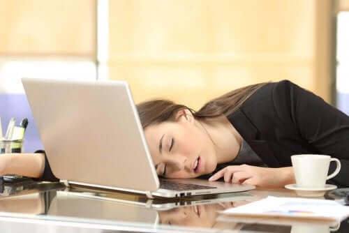En kvinne med narkolepsi som sover på den bærbare datamaskinen sin.
