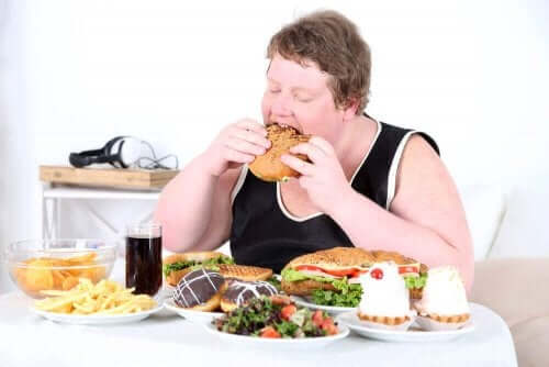 En overvektig kvinne som spiser masse unsunn mat.