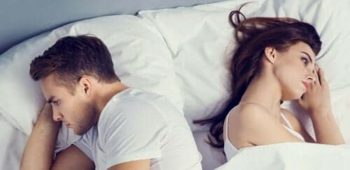 Et par som ligger med ryggen mot hverandre i sengen og tydelig har problemer.