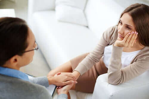 Kvinne holder hender med en terapeut