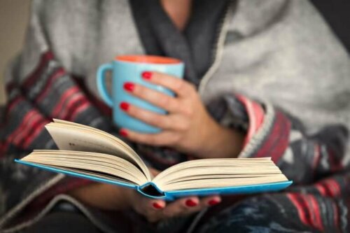 En kvinne leser en bok og drikker varm drikke: prøv det for å ta vare på den mentale helsa di