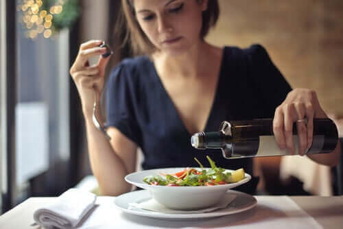 En kvinne som tilsetter olivenolje i en salat.